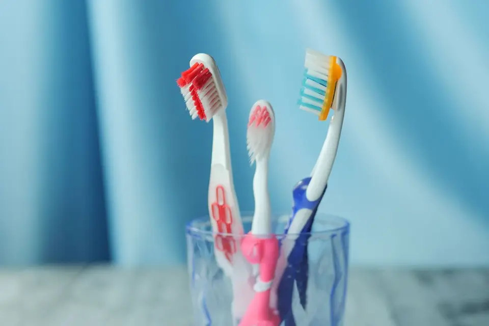 A trio of vibrant toothbrushes in a glass on a blue background, emphasizing dental hygiene.