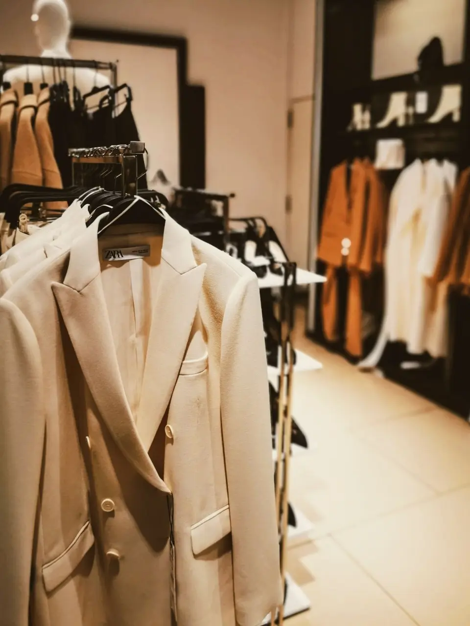 A variety of stylish beige suits showcased in a modern retail store, ideal for fashion enthusiasts.
