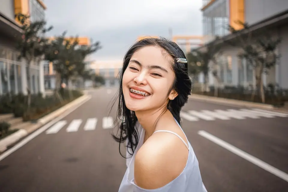 Happy young woman with braces smiling brightly on an outdoor road.