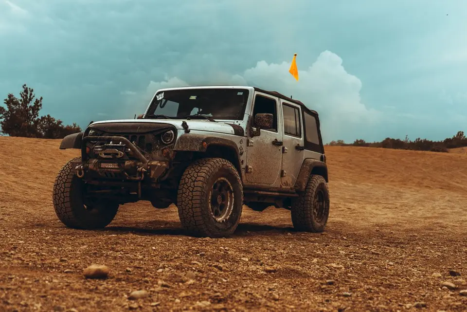Mud-covered Jeep parked in a desert setting, perfect for off-road enthusiasts.